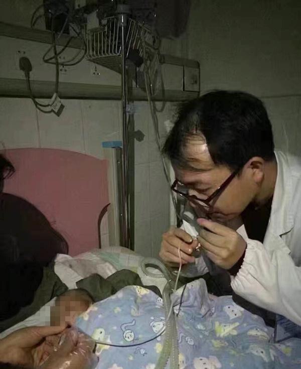 重癥監護室停電醫生用嘴吸出堵在孩子氣管內的粘稠痰液。